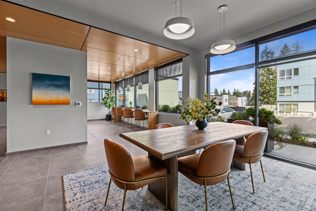 a dining area with a wooden table and chairs and large windows
