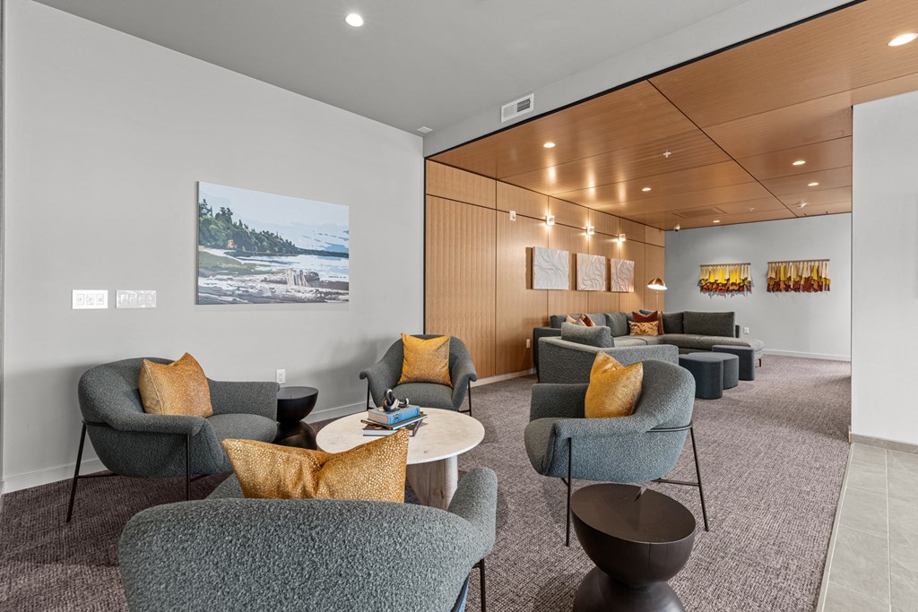 a lounge area with chairs and tables and a painting on the wall