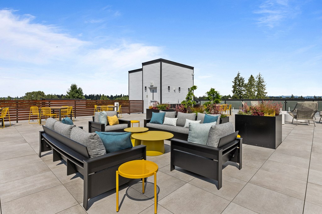 a rooftop patio with couches and tables on a sunny day