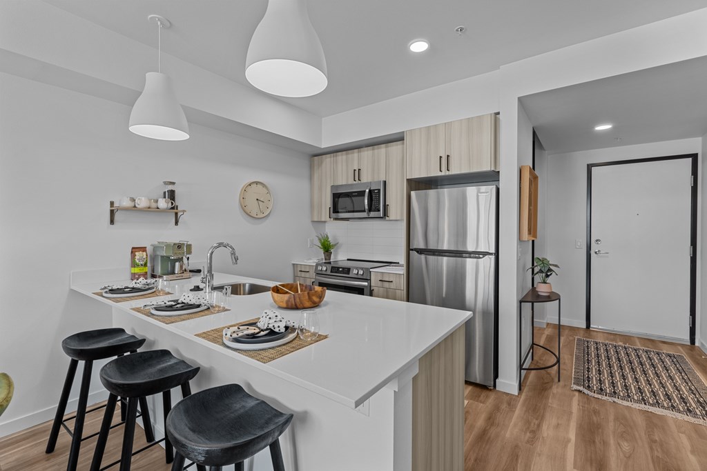 a kitchen with a white counter top and a stainless steel refrigerator