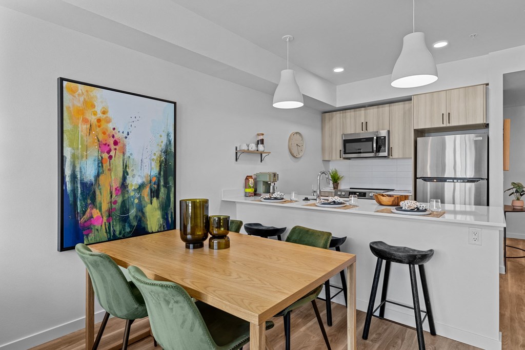 an open kitchen and dining area with a wooden table and bar stools