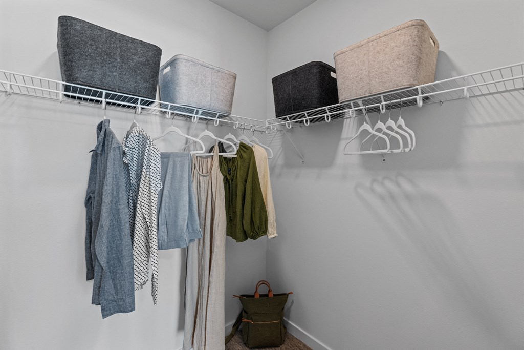 a walk in closet with clothes and baskets on the wall and a rack with towels