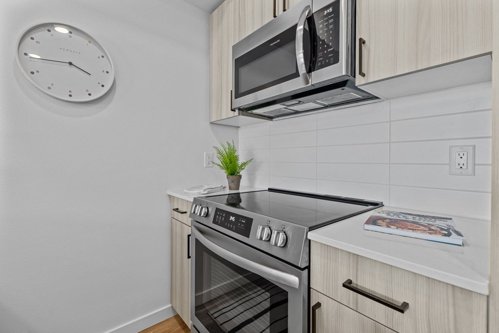 a kitchen with a stove and microwave and a clock on the wall