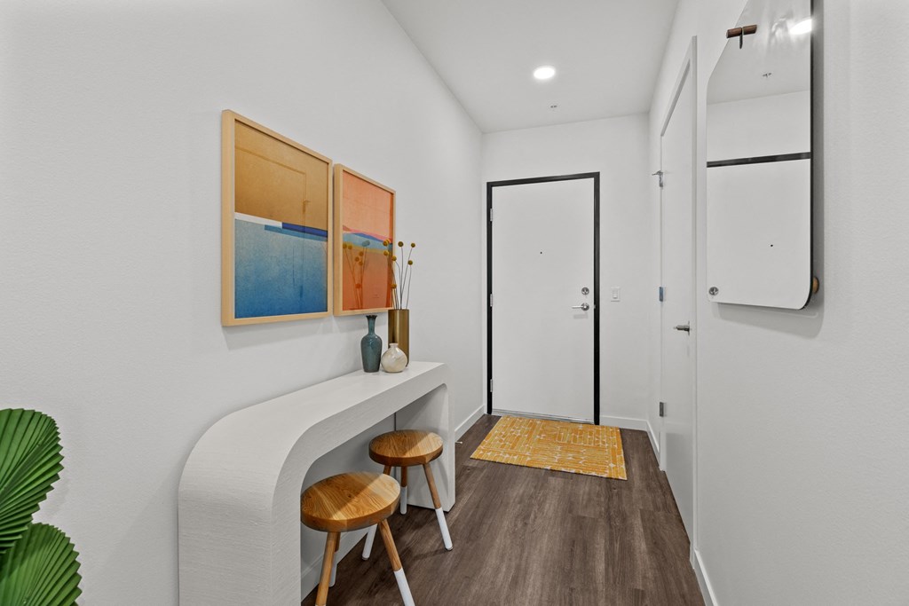 a room with a long counter with two stools and a white door