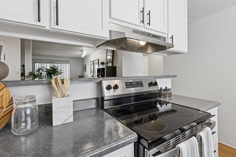 A modern kitchen with a stove top oven and white cabinets.