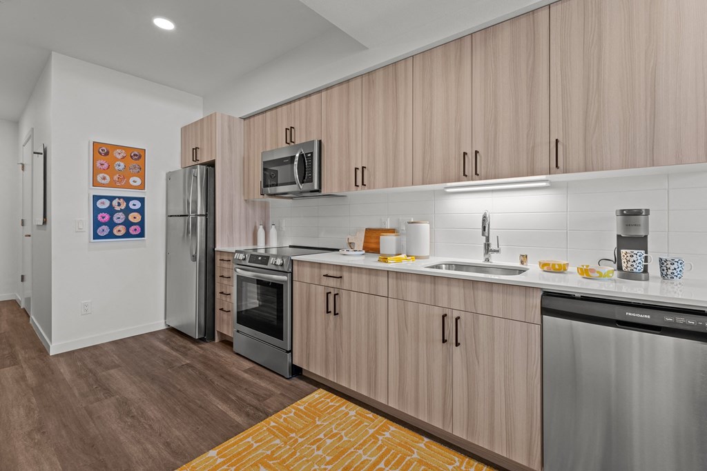 a kitchen with wooden cabinets and stainless steel appliances and a yellow rug