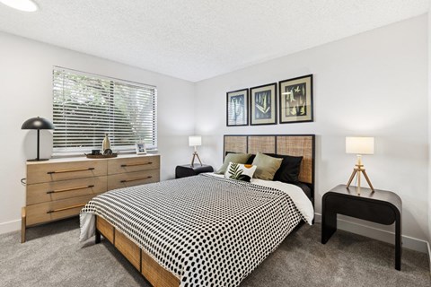 A bedroom with a bed, nightstands, and pictures on the wall.
