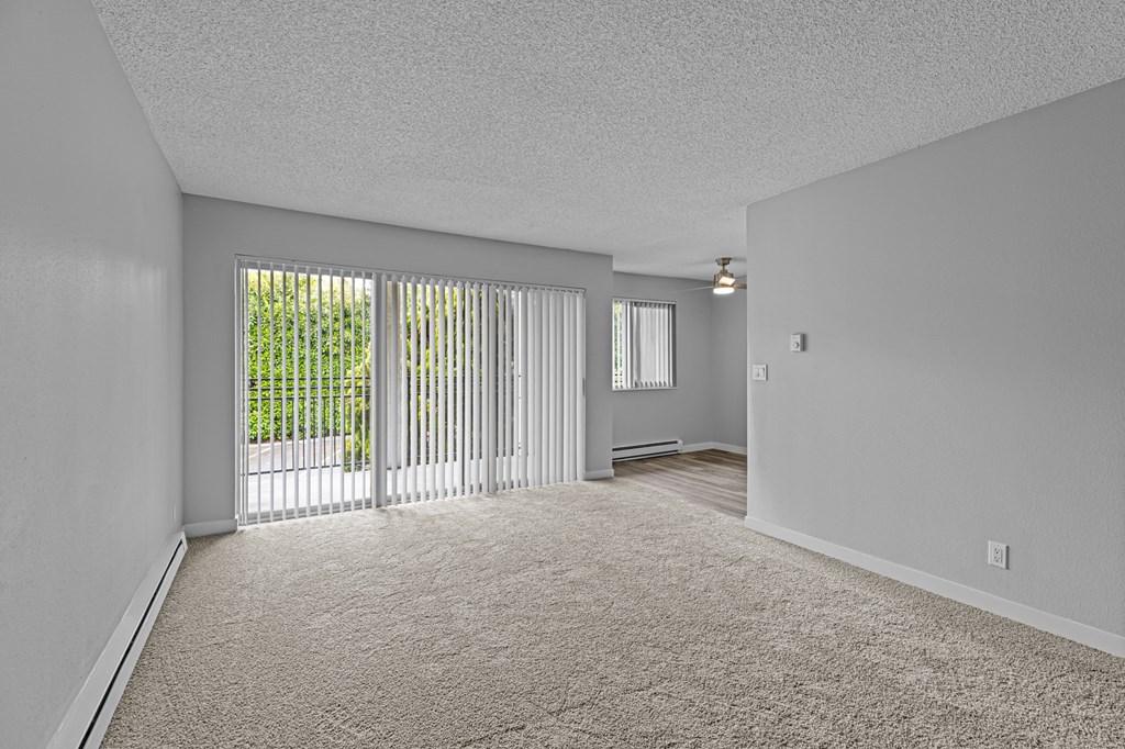 an empty living room with sliding glass doors to a patio