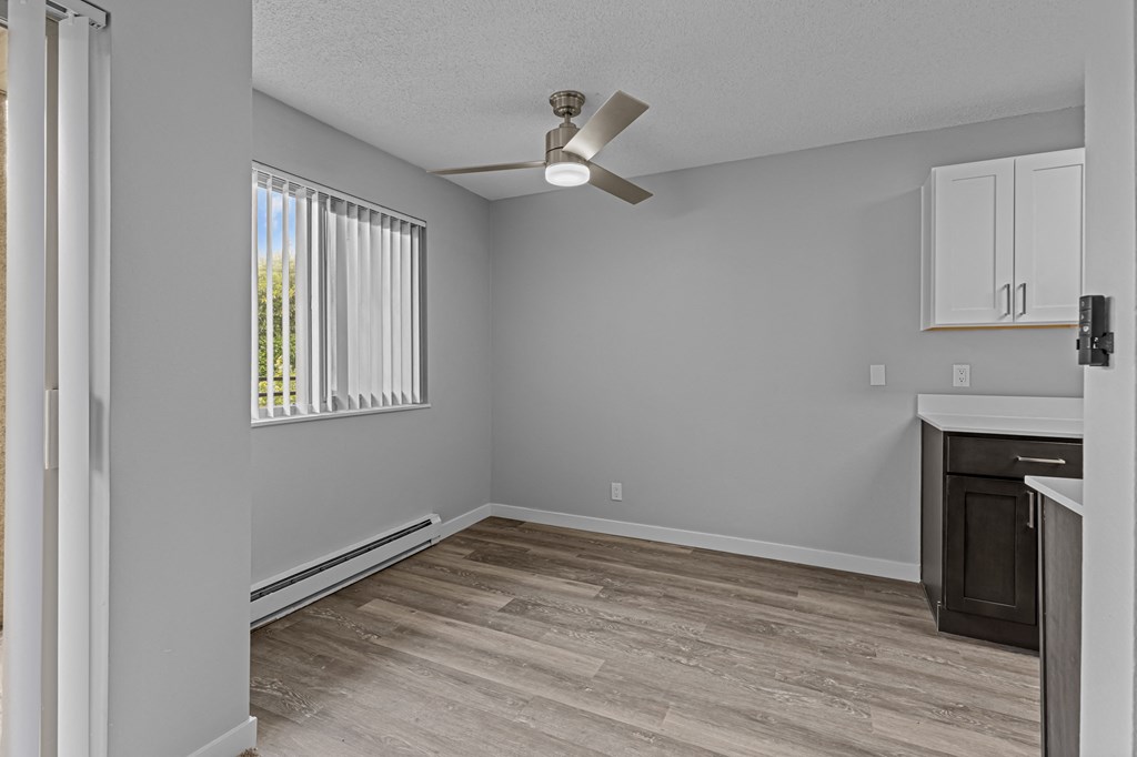 an empty living room with a ceiling fan and a window