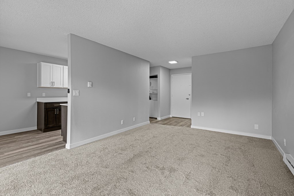 an empty living room with white walls and a white kitchen