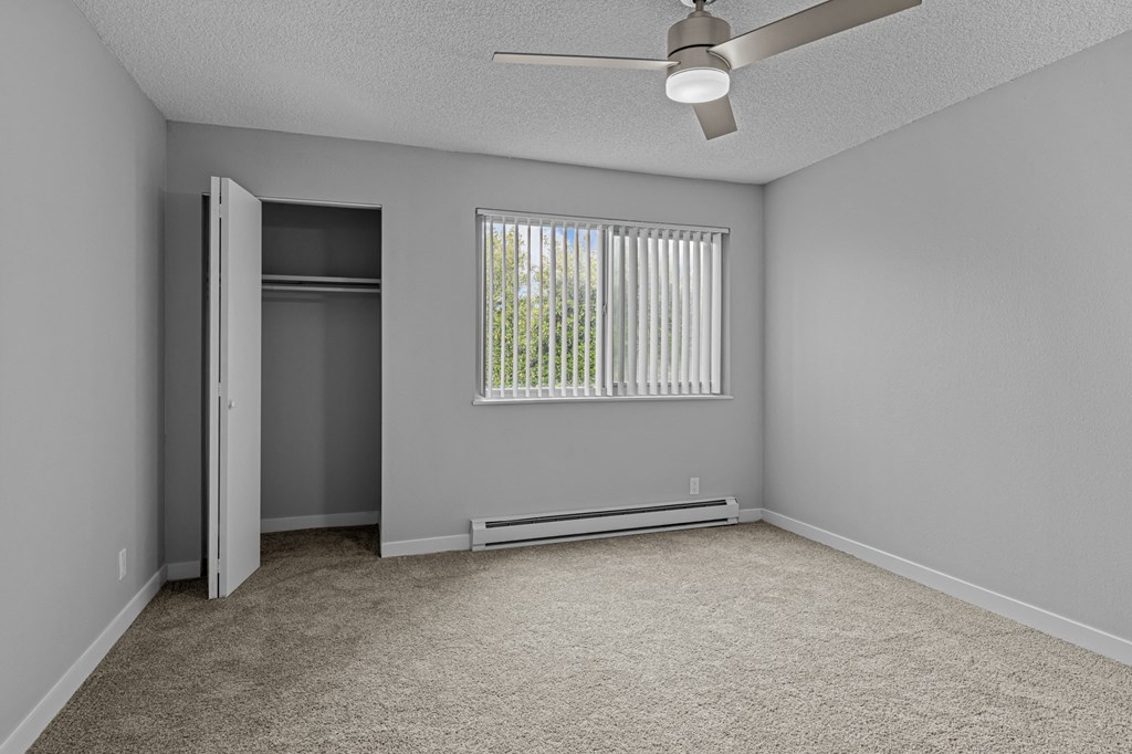 an empty bedroom with a window and a closet