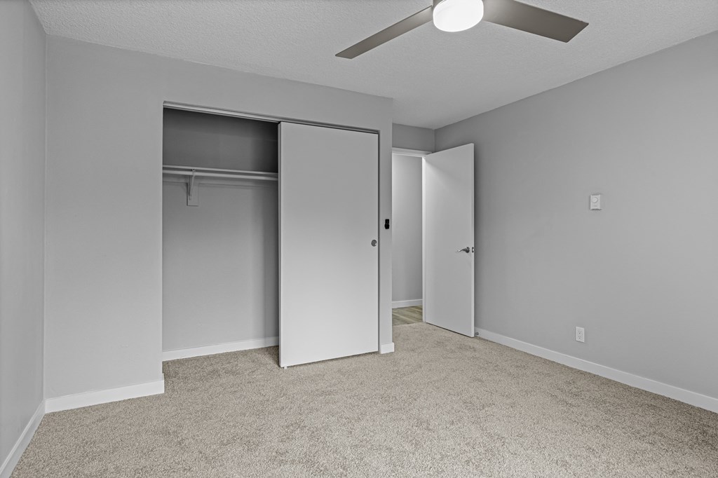 an empty bedroom with a closet and a ceiling fan