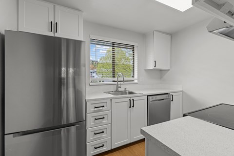 A kitchen with a refrigerator, sink, and cabinets.