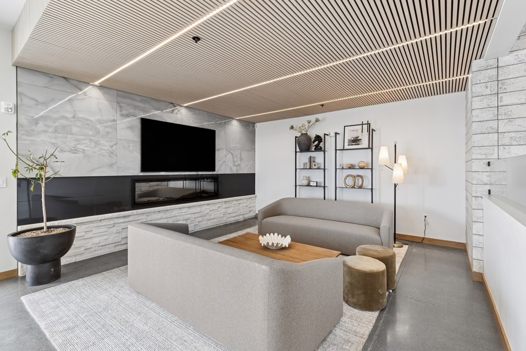 A modern living room with a grey sofa and a stone fireplace.