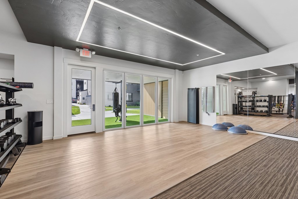 A gym with a mirrored wall and a wooden floor.