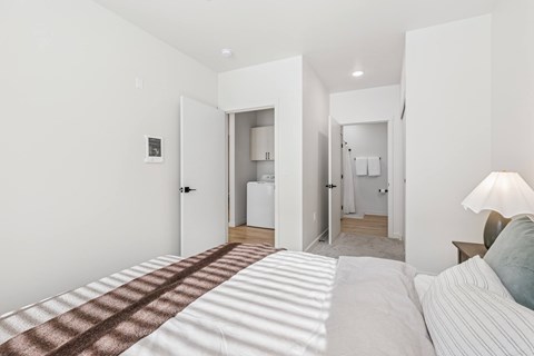 A bedroom with a bed in the foreground and a bathroom visible through a doorway.