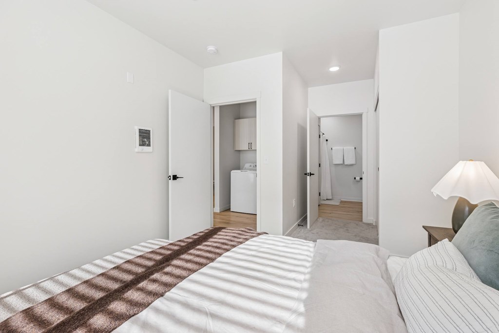 A bedroom with a bed in the foreground and a bathroom visible through a doorway.