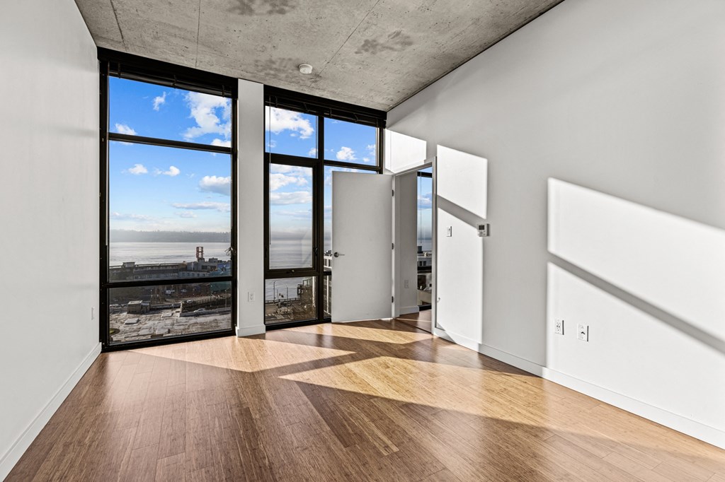 an empty living room with windows and a view of the ocean