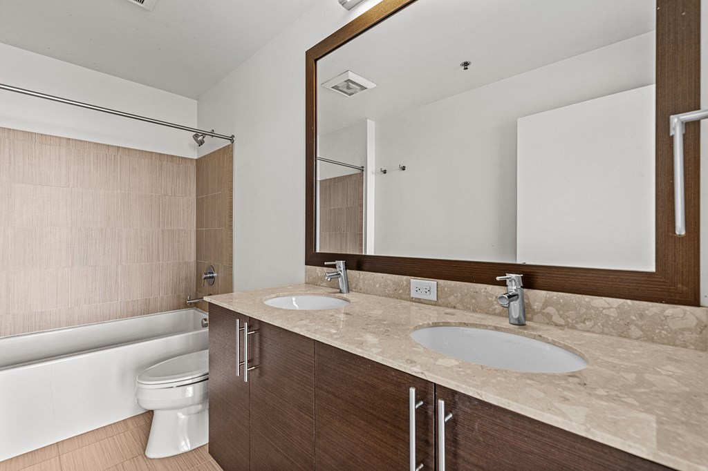 a bathroom with two sinks and a toilet and a large mirror