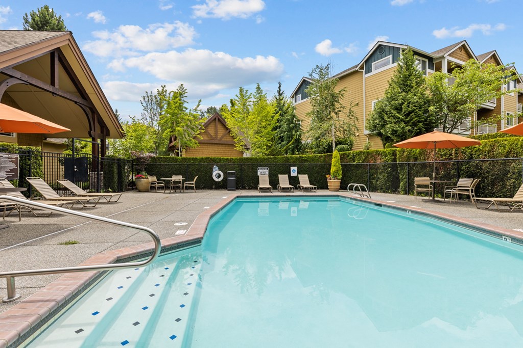a swimming pool with lounge chairs and umbrellas in front of a building