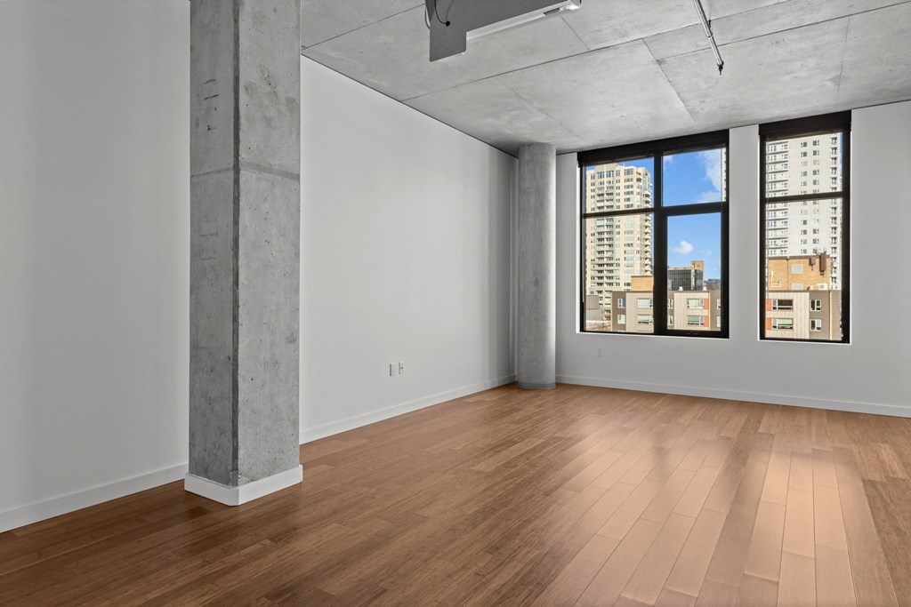 an empty living room with wood floors and a window