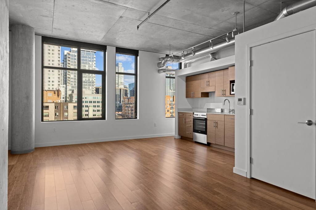 an empty living room with a kitchen and a view of the city