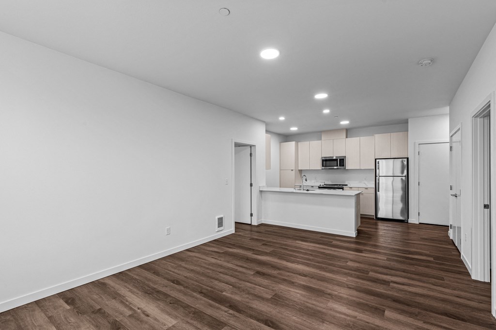 the living room and kitchen in a new home with white walls and wood flooring