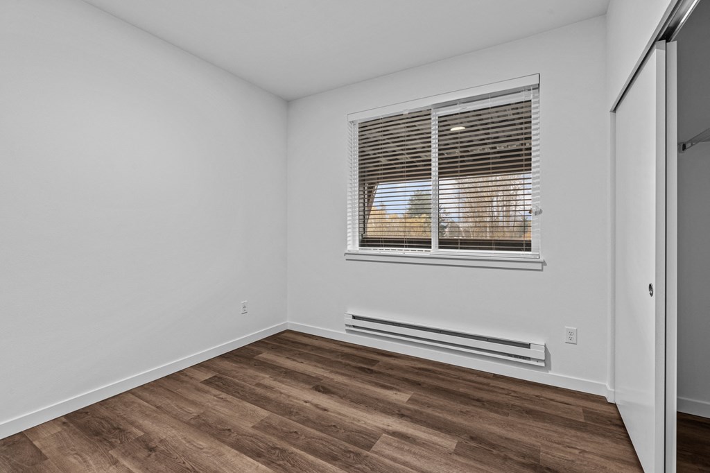 the living room of an apartment with wood flooring and a window