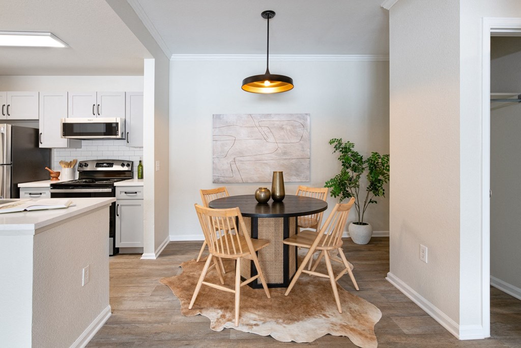 a dining area with a table and chairs and a kitchen in the background