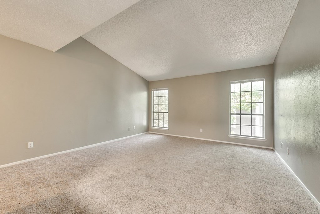 an empty living room with a window and carpet