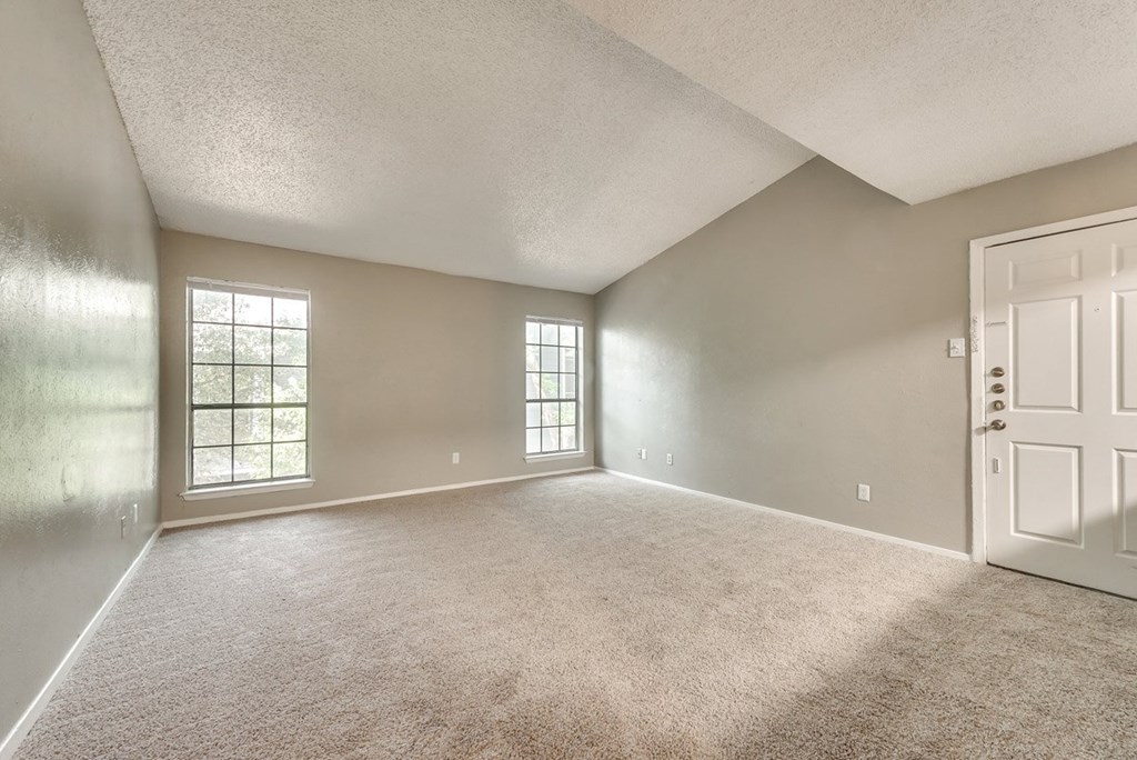 an empty living room with a white door and carpet