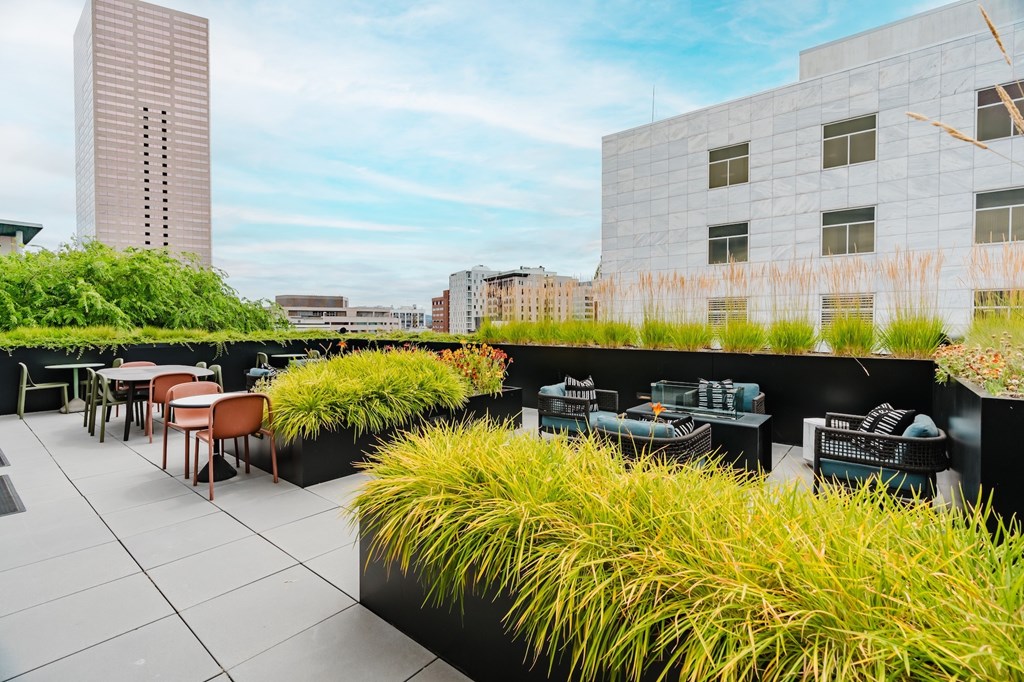 A rooftop patio with tables and chairs overlooking a cityscape.