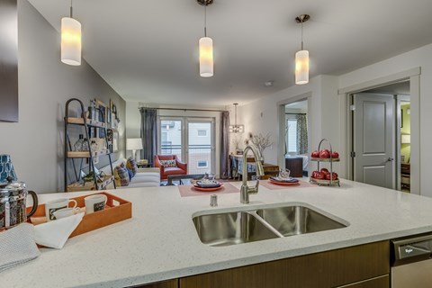 a kitchen with a sink and a view into a living room