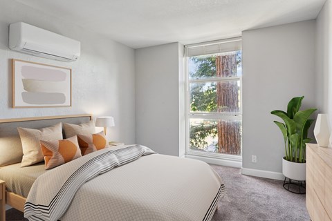 A bedroom with a large bed and a window overlooking a forest.