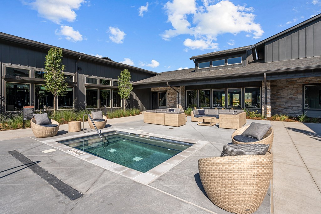 a patio with a pool and chairs in front of a building