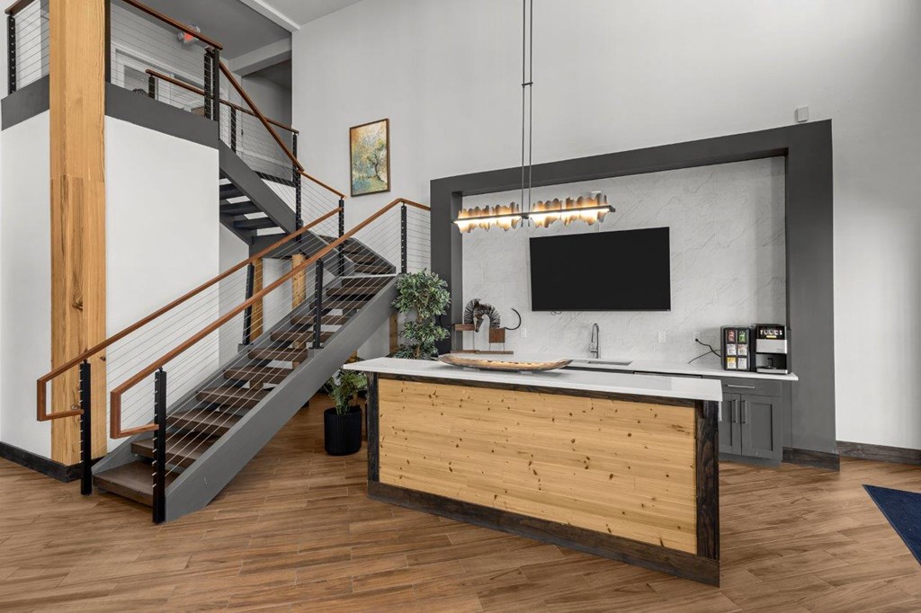 A modern kitchen with a wooden counter and a staircase.