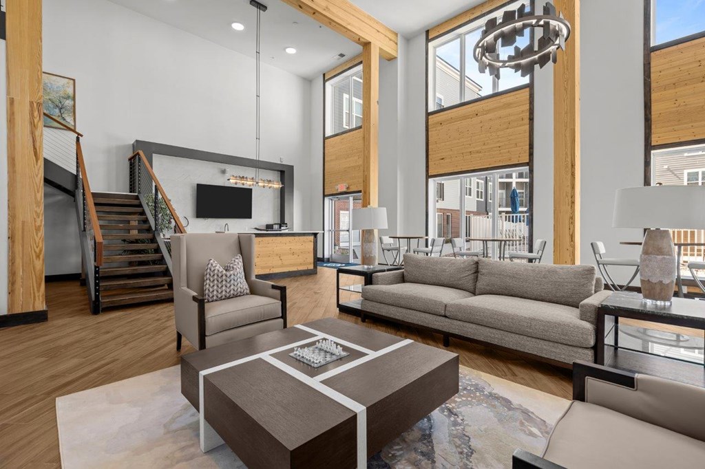 A modern living room with a staircase and a kitchen area in the background.