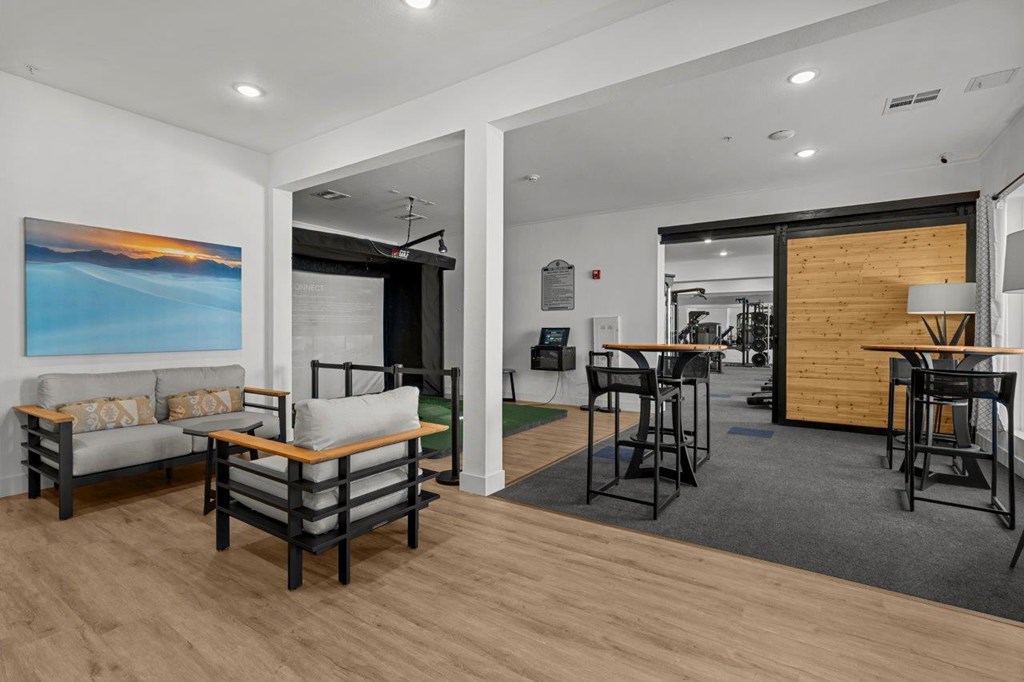 A living room with a grey couch and a painting on the wall.