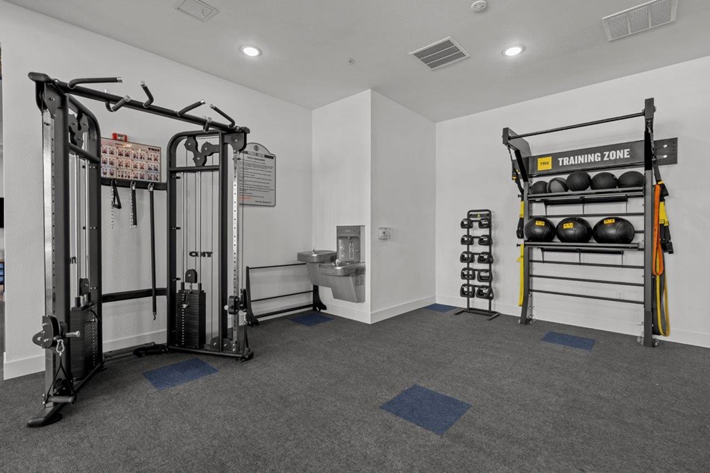 A gym with a weightlifting area and a rack of kettlebells.