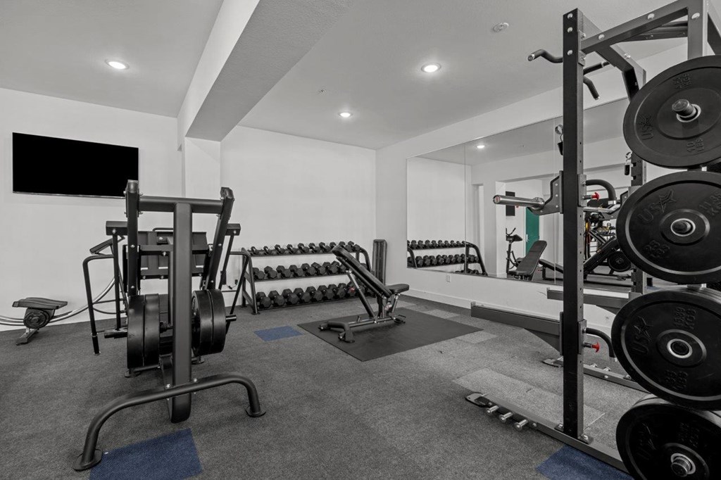 A black and white photo of a gym with weights and exercise equipment.