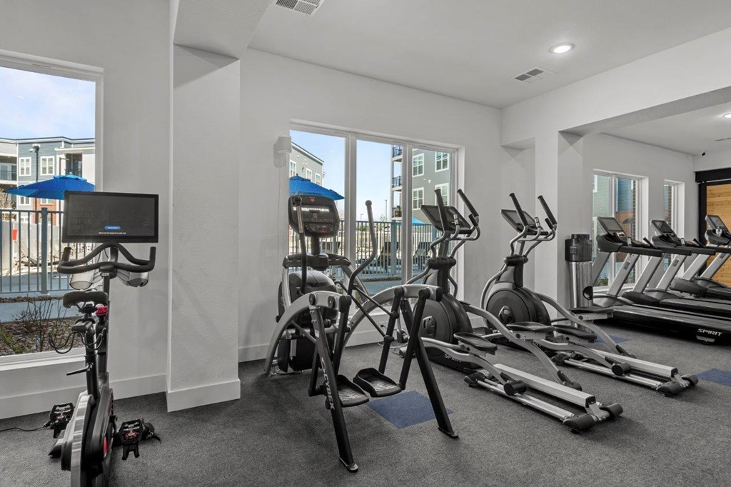 A gym with a row of treadmills and exercise bikes.