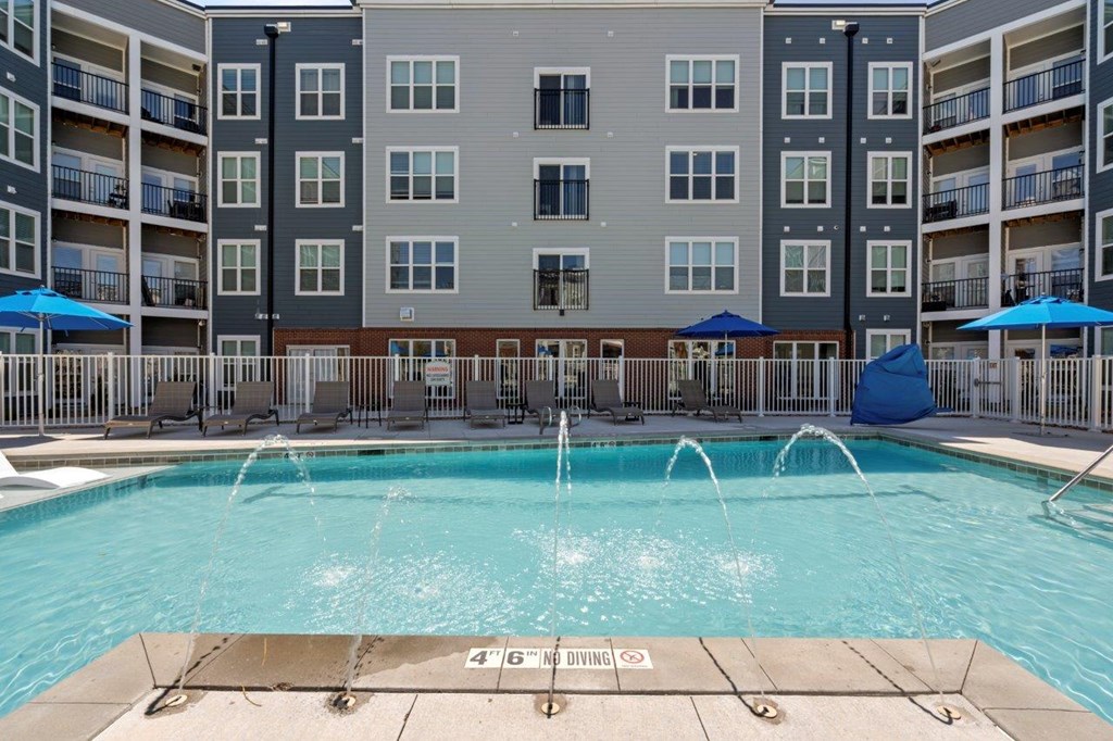 A large swimming pool in front of apartment buildings with a 4'6