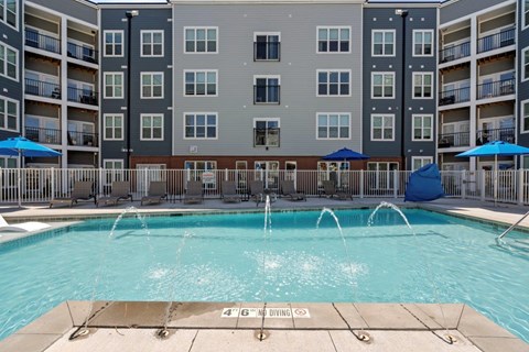 A large swimming pool in front of apartment buildings with a 4'6