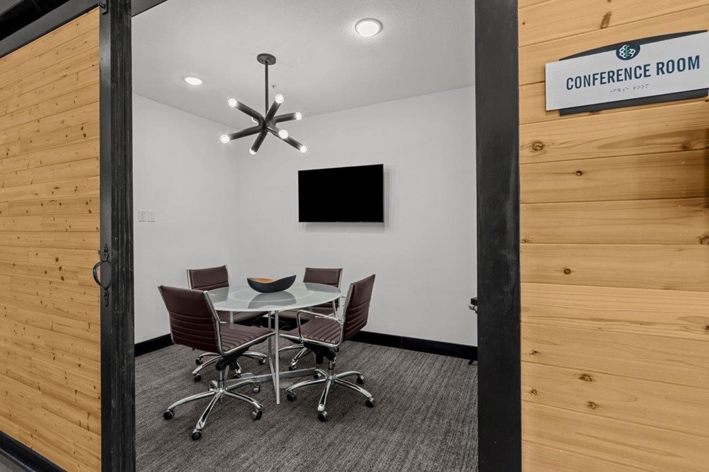 A conference room with a table and chairs and a sign on the wall.