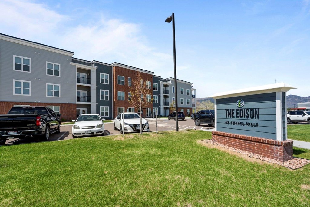 The Edison apartments are located in a grassy area with cars parked in the background.