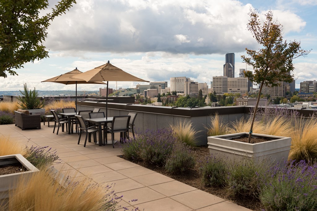 A patio with a table and chairs overlooking a city skyline.