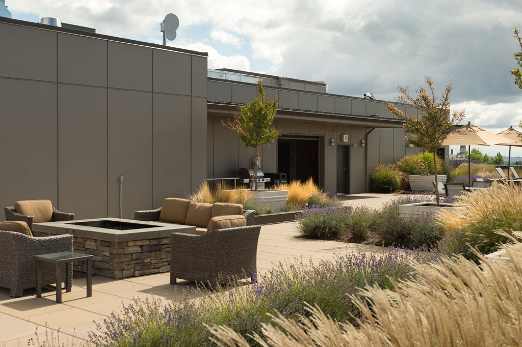 A modern outdoor seating area with a stone wall and wicker furniture.