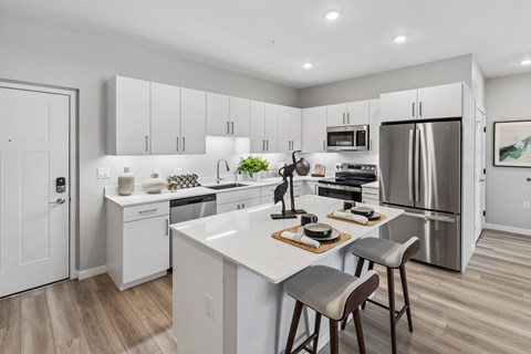 A modern kitchen with a white island and stainless steel appliances.