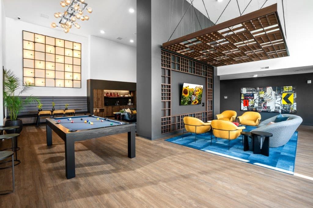 a pool table in the lobby of a club with yellow chairs