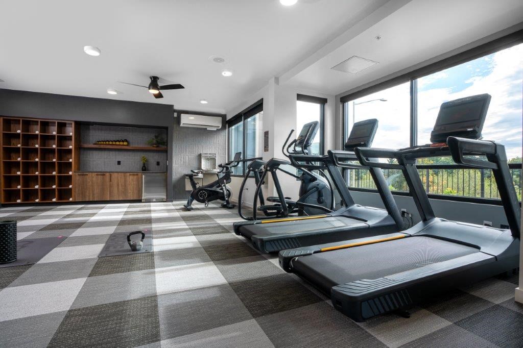 the gym is equipped with cardio equipment and a large window